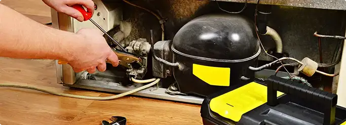 Refrigerator repair technician fixing the compressor and wiring in North Las Vegas, NV