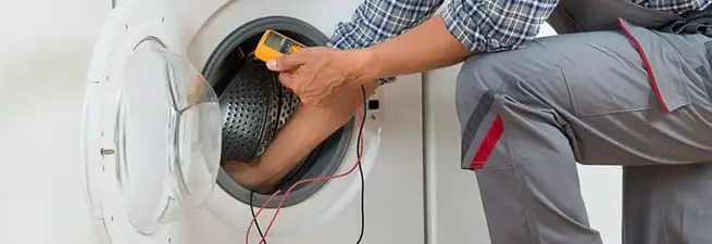 Dryer repair technician inspecting and repairing a clothes dryer in Las Vegas, NV