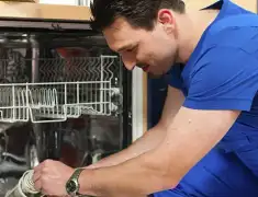Dishwasher repair technician inspecting and servicing an open dishwasher in Las Vegas, NV