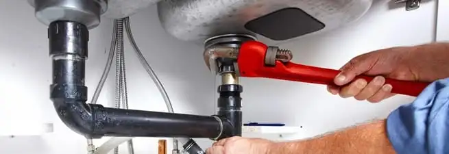 Garbage disposal repair technician tightening the sink drain and disposal connection in Las Vegas, NV