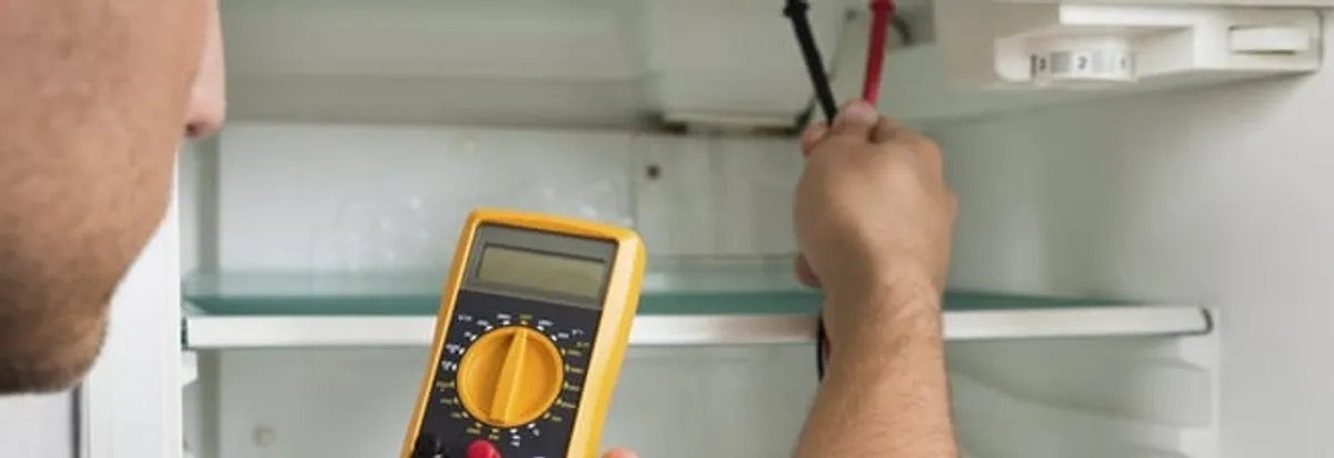 Refrigerator repair technician testing electrical components with a multimeter in Las Vegas, NV