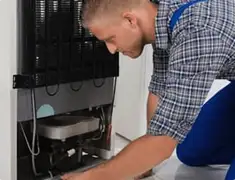 Refrigerator repair technician servicing the compressor and condenser area in Las Vegas, NV