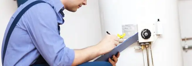 Water heater repair technician inspecting the unit and recording service notes in Las Vegas, NV